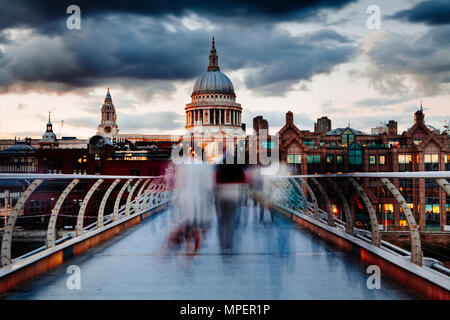 Temprano por la tarde en el Puente del Milenio de Londres con gente cruzando en el desenfoque de movimiento y una vista de la Catedral de San Pablo.