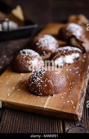 Deliciosas galletas de cacao con relleno de coco, decorados con chocolate y coco rallado
