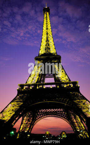 Vista de la Torre Eiffel, cerca de Champ de Mars, mirando hacia el atardecer, mostrando luces de una con poco esponjosas nubes y resplandor crepuscular, París, Francia Foto de stock