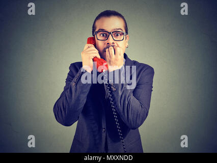 Hombre elegante en traje recibir noticias alarmantes sobre el teléfono y mirando a la cámara con miedo.