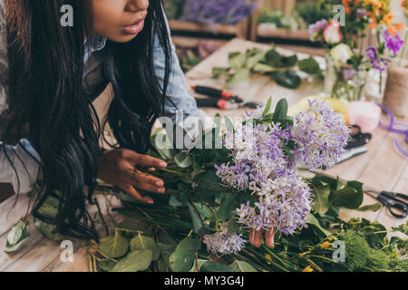 Captura recortada del joven afroamericana arreglar las flores y hojas verdes en flower shop