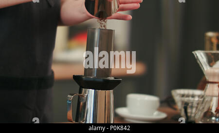 Barista adición de café molido y vertiendo agua caliente Foto de stock