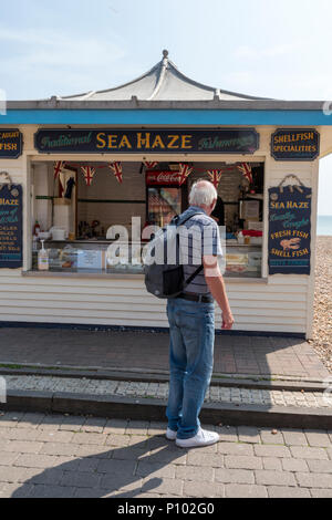 Hombre mirando una pescaderos cala en el paseo marítimo de la playa de Brighton en East Sussex. puesto en el mercado en el paseo marítimo de la playa de Brighton. Foto de stock