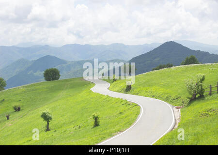 Curvas sinuosas carreteras rurales en prados verdes y hermosas vistas a la montaña en un paraje natural en la primavera