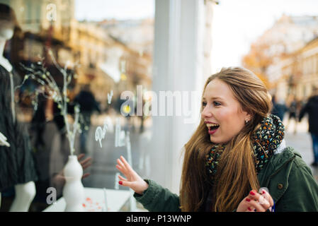 Atractiva mujer joven de cabellos largos se excita delante de la ventana de compra Foto de stock