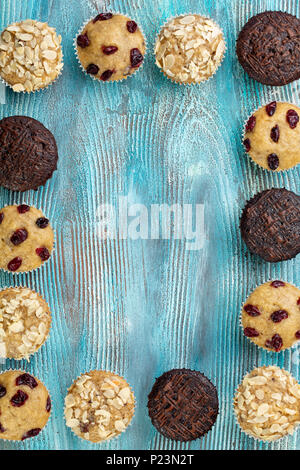 Chocolate chip muffins caseros como marco sobre azul mesa de madera. Espacio de copia Foto de stock