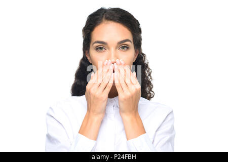 Hermosa morenita empresaria en camisa blanca cerrando la boca con las manos, aislado en blanco Foto de stock