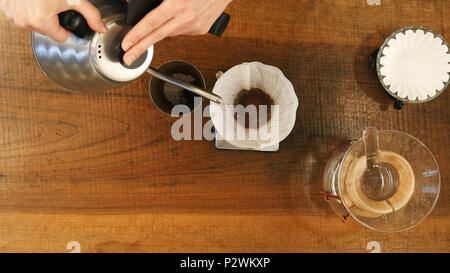 Cafetera de goteo de mano , barista verter agua sobre el café tierra con filtro Foto de stock