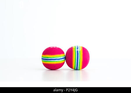 Par de pequeñas bolas de juguete colorido con tiras de colores juntos , aislados sobre un fondo blanco.