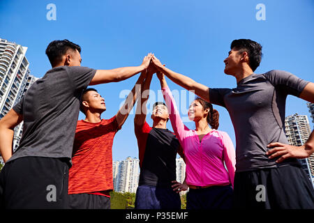 Equipo de deportistas y adultos jóvenes asiáticos sportswoman poniendo manos juntos para mostrar la unidad y espíritu de trabajo en equipo. Foto de stock