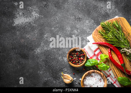 Especias, hierbas aromáticas y utensilios de cocina a través de la tabla de piedra negra. Fondo de alimentos. Vista superior, espacio de copia. Foto de stock