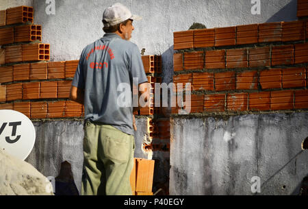 Em construção Pedreiros levantando parede de tijolos.