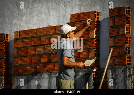 Em construção Pedreiros levantando parede de tijolos.