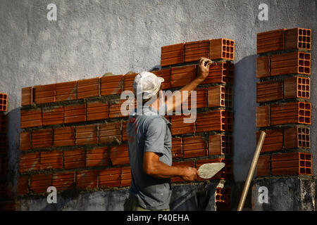 Em construção Pedreiros levantando parede de tijolos.
