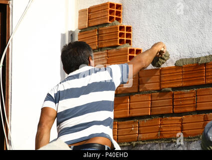 Em construção Pedreiros levantando parede de tijolos.