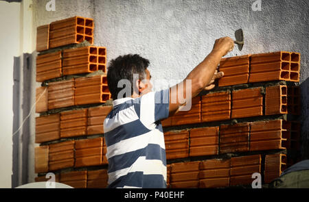 Em construção Pedreiros levantando parede de tijolos.