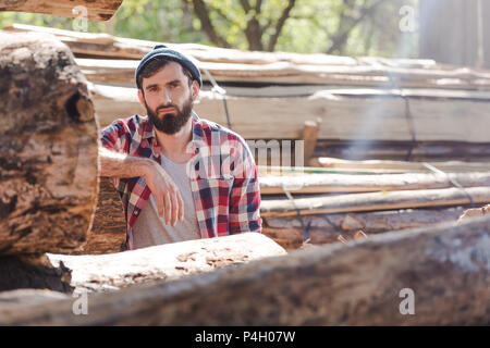 Leñador barbudo en camisa a cuadros en sawmill permanente Foto de stock
