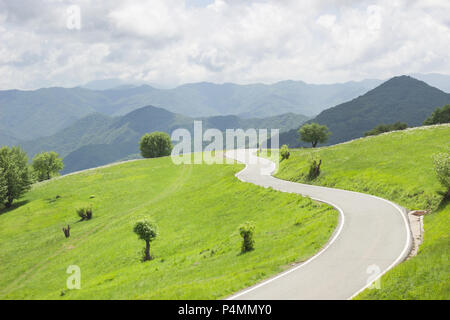 Curvas sinuosas carreteras rurales en prados verdes y hermosas vistas a la montaña en un paraje natural en la primavera