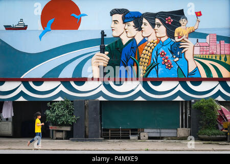 Niños menores de un gigantesco mural de propaganda comunista en la provincia de Nam Dinh, Vietnam - Tipo unter einem riesigen kommunistisches Dinh-Provinz Propaganda-Wandgemälde in der Nam, Vietnam Foto de stock