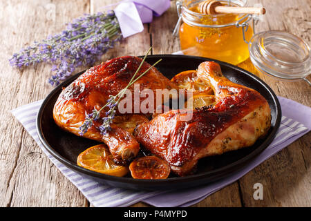 Deliciosa comida francesa: trimestre piernas de pollo asadas con miel de lavanda, especias y limón cerca en una placa horizontal sobre la mesa. Foto de stock