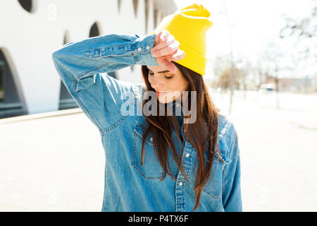 España, Barcelona, joven mujer vistiendo la tapa amarilla y camisa denim Foto de stock