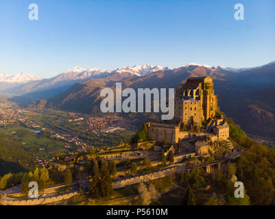 Vista aérea de la antigua abadía medieval encaramado en la cima de la montaña, de fondo de los Alpes nevados al amanecer. Sacra di San Michele (italiano) - Saint Michel Abbey (en inglés Foto de stock