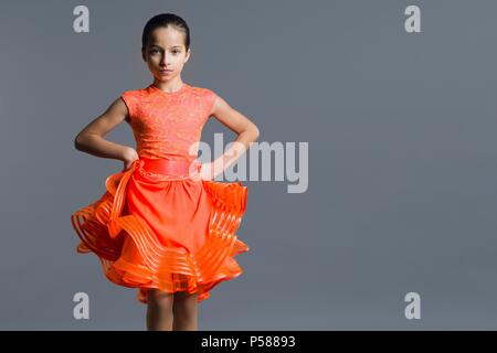 Retrato de una niña 9-10 años bailarina. Deportes, baile latino. Chica en un vestido de color naranja sobre fondo gris de studio, espacio de copia Fotografía de stock - Alamy