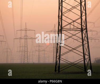 Postes de electricidad y las líneas de suministro de energía al amanecer. Foto de stock