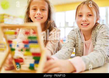 Dos niñas como estudiantes de la escuela primaria son el cálculo con el ábaco Foto de stock