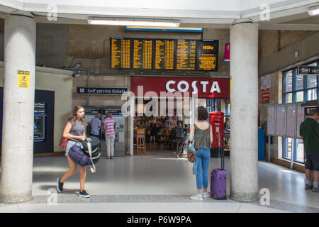 Dentro de la taquilla en Guildford estación ferroviaria, con una costa coffee shop y pasajeros comprando los boletos de maquinas de autoservicio, Surrey, Reino Unido Foto de stock