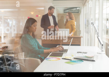 Diseñador gráfico femenino usando un portátil en una mesa Foto de stock