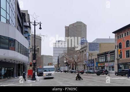 Winnipeg, Manitoba, Canadá - 2014-11-17: Una persona en silla de ruedas cruzar la intersección de Portage Ave y Smith St en invierno
