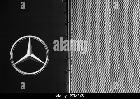 El símbolo y la brillante estrella de Mercedes Benz en la moderna fachada de un concesionario de coches. Foto de stock