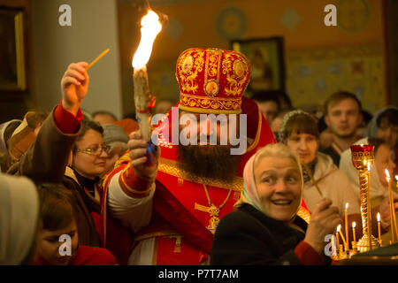 Belarús, Gomel, 8 de abril de 2018. El Monasterio de Nikolsky. La celebración de la Pascua Ortodoxa. El sacerdote lleva una vela con el fuego sagrado en la multitud de j Foto de stock