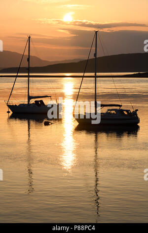 Pleno sol reflejado en el agua de la bahía en el norte Ardmucknish Connel y Oban Aeropuerto con veleros en silueta Foto de stock