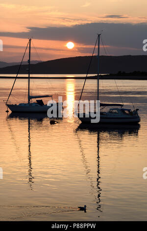 Pleno sol ball reflexionando sobre el agua de la bahía en el norte Ardmucknish Connel y Oban Aeropuerto con veleros y Gaviota en silueta Foto de stock