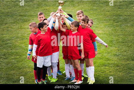 Niños - los niños de fútbol los jugadores celebrando con un trofeo después de coincidir en el campo de fútbol