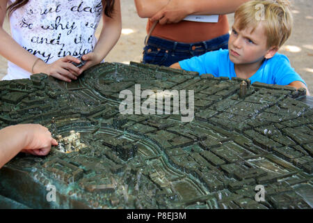 Tras el muchacho explainations de su madre, explicando la ciudad de Lyon, en un mapa de contornos de bronce - Ciudad de Lyon, Francia. Foto de stock