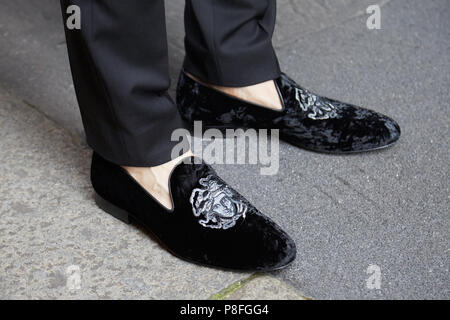 Milán - 16 de junio: el hombre con zapatos Versace de terciopelo negro con cabeza de Medusa antes de Versace Fashion la Semana de la de Milán street style