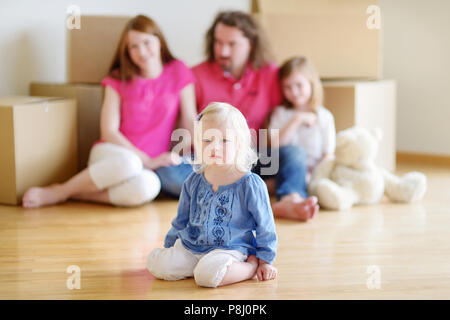 Poco niño niña con un juguete moviéndose en su nuevo hogar con sus padres y una hermana Fotografía de stock - Alamy