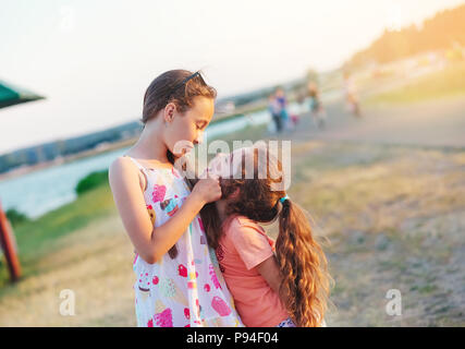 Dos chicas que se divierten poco feliz y abrazando a pradera a día de verano