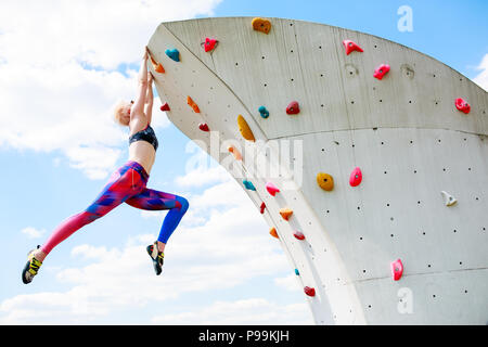 de sportswoman en leggings colgado en la pared para escalar en contra el cielo azul Fotografía de stock - Alamy