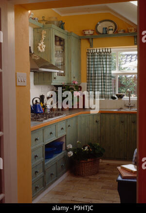 Color verde pastel armarios y unidades en la pequeña cocina naranja pálido  con extensión marcada verde cortinas Fotografía de stock - Alamy