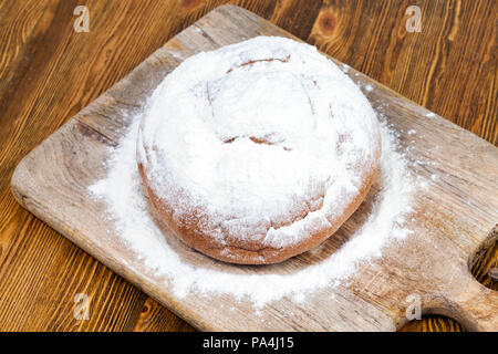 Nueva ronda pan espolvoreado con harina de trigo blanca durante su preparación, el primer plano en la parte superior Foto de stock