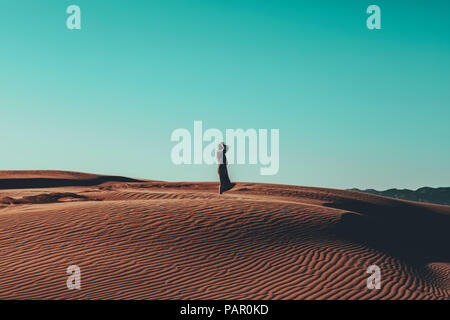 Mujer joven con cabello alborotado de pie en el paisaje desierto Foto de stock