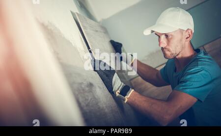 La sustitución de las baldosas del baño. Trabajador del Cáucaso en su 30s instalando nuevos azulejos de cerámica. Foto de stock