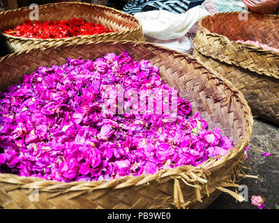 Con cestas llenas de flores coloridas pertals utilizado para ofrendas diarias vendidas en el mercado de Ubud, Bali, Indonesia Foto de stock