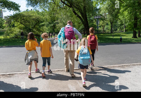 El hombre escolta de jóvenes estudiantes de la escuela a casa en Central Park, Nueva York, EE.UU. Foto de stock