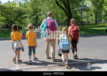El hombre escolta de jóvenes estudiantes de la escuela a casa en Central Park, Nueva York, EE.UU. Foto de stock