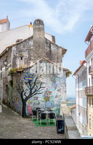 Linda área de asientos al aire libre, delante del edificio pintado artístico, en el histórico distrito junto a la Universidad de Coimbra, Portugal.